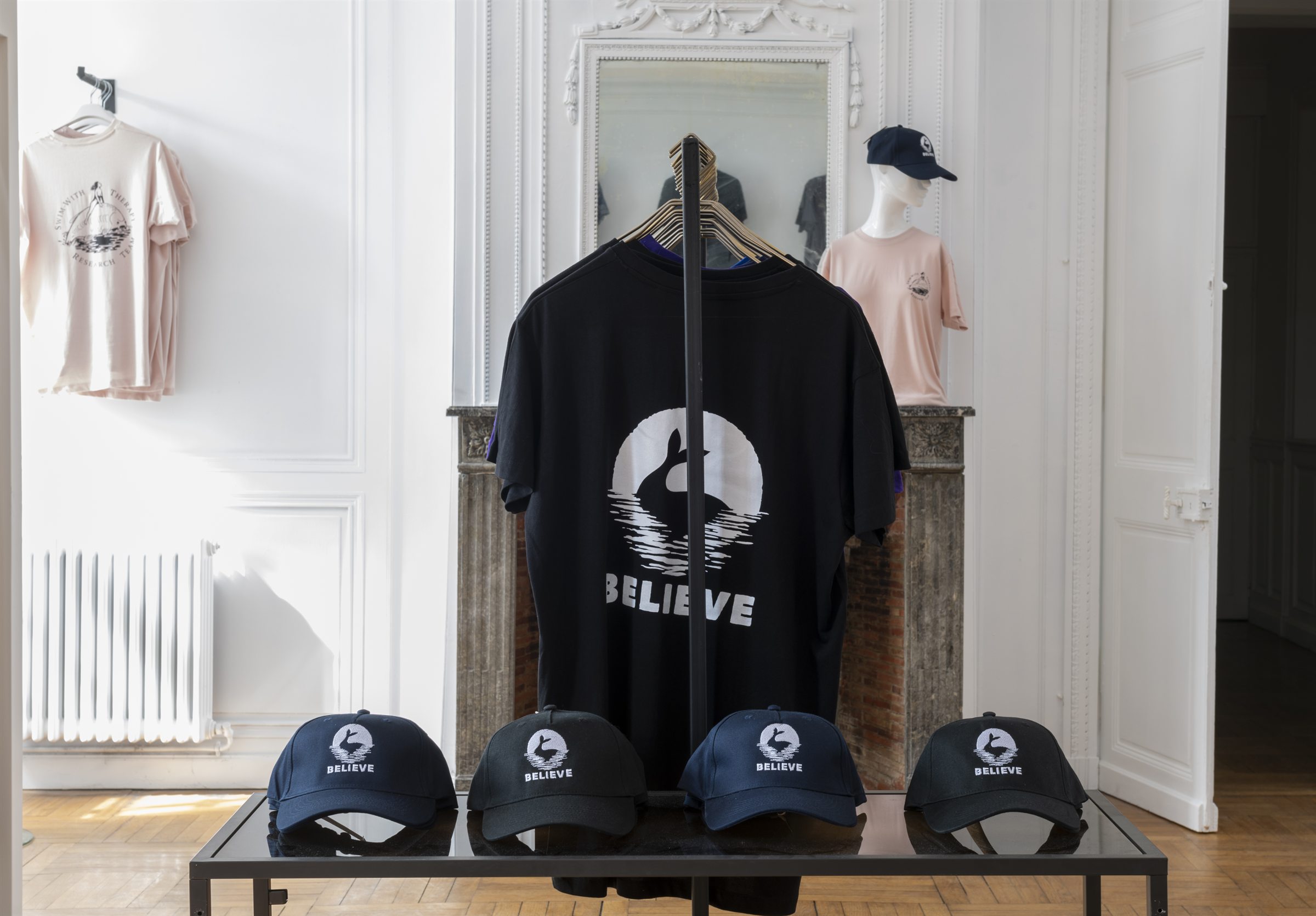 T-shirts et casquettes Believe présentés devant une cheminée